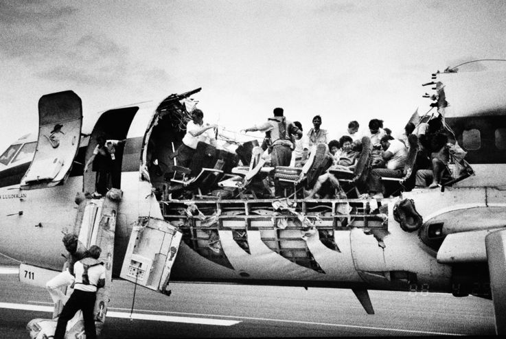 FILE - Copilot Mimi Tompkins helps a man slide down a chute of a severely damaged Aloha Airlines 737 jet shortly after arrival in Kahului, Hawaii in this April 28, 1988 file photo. Pilot Robert Schornstheimer, at front of damaged section, looks on.The jet blew open at 24,000 feet when a 20-foot section of the aircraft