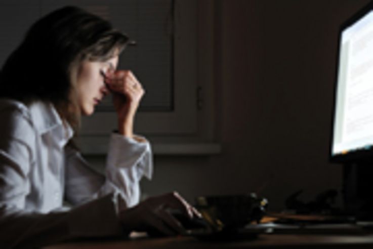 Young tired business woman with headache sitting at computer in workplace - night overtime work